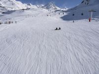 a ski slope full of people with skiers up to the top of it and hills in the background