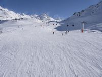 a ski slope full of people with skiers up to the top of it and hills in the background