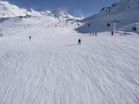 a ski slope full of people with skiers up to the top of it and hills in the background