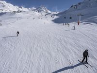 a ski slope full of people with skiers up to the top of it and hills in the background