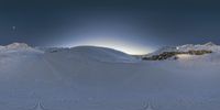 a ski slope with many tracks in the snow under a blue sky with a moon