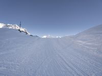 a person snow skiing down a ski slope in the mountains under a blue sky with some clouds