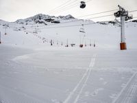 skiers on the ski slopes near ski lifts in snow covered area, snow covered mountains and sky