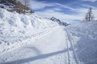 a ski trail in the mountains is made of snow with many tracks on it while the road goes through