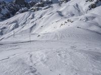 a skier on a snowy mountain side with snow surrounding him and several wires in the foreground