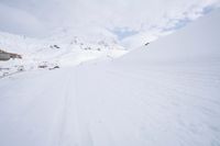 a person skiing down a snowy mountain slope in the winter and with a snowy mountainside in the background