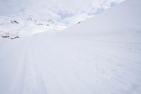 a person skiing down a snowy mountain slope in the winter and with a snowy mountainside in the background