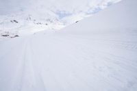 a person skiing down a snowy mountain slope in the winter and with a snowy mountainside in the background