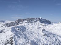 a skier standing on top of a snowy mountain side with mountains in the background in the foreground