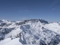 a skier standing on top of a snowy mountain side with mountains in the background in the foreground