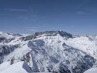 a skier standing on top of a snowy mountain side with mountains in the background in the foreground