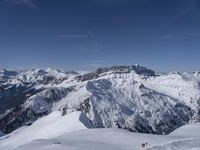 a skier standing on top of a snowy mountain side with mountains in the background in the foreground