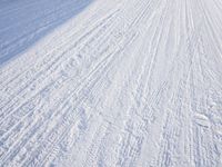 a person riding skis down a snow covered slope covered in snowboarding and holding two poles