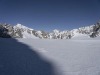 a skier skiing through the snow by some mountains and boulders and clouds in the sky