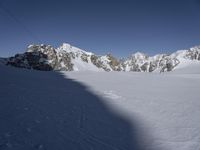 a skier skiing through the snow by some mountains and boulders and clouds in the sky