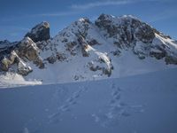 a lone person is skiing alone in the snow with mountains behind them and a blue sky