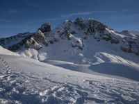 a lone person is skiing alone in the snow with mountains behind them and a blue sky