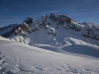 a lone person is skiing alone in the snow with mountains behind them and a blue sky