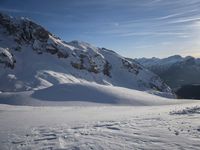 a lone person is skiing alone in the snow with mountains behind them and a blue sky