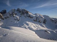 a lone person is skiing alone in the snow with mountains behind them and a blue sky