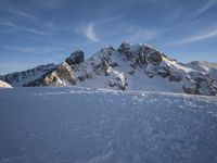 a lone person is skiing alone in the snow with mountains behind them and a blue sky