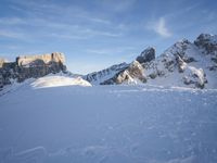 a lone person is skiing alone in the snow with mountains behind them and a blue sky