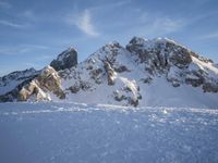 a lone person is skiing alone in the snow with mountains behind them and a blue sky