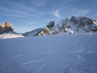 a lone person is skiing alone in the snow with mountains behind them and a blue sky