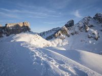 a lone person is skiing alone in the snow with mountains behind them and a blue sky