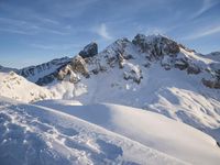 a lone person is skiing alone in the snow with mountains behind them and a blue sky