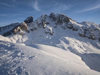 a lone person is skiing alone in the snow with mountains behind them and a blue sky