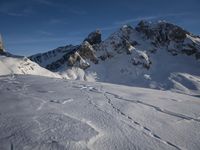a lone person is skiing alone in the snow with mountains behind them and a blue sky