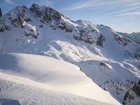 a lone person is skiing alone in the snow with mountains behind them and a blue sky