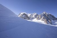 a person skis down a snowy mountain slope with a mountain behind them and wires in the air