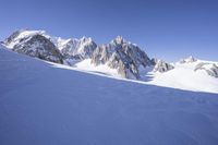 a person skis down a snowy mountain slope with a mountain behind them and wires in the air