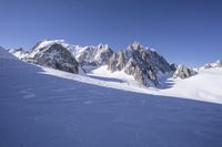 a person skis down a snowy mountain slope with a mountain behind them and wires in the air