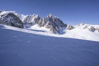 a person skis down a snowy mountain slope with a mountain behind them and wires in the air