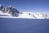 a person skis down a snowy mountain slope with a mountain behind them and wires in the air