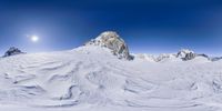 a person skiing down a large snow covered slope next to some mountains under a full moon