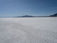 a group of people riding snow skis on top of a salt flat surface,