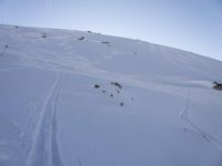 a person is skiing down the snow covered mountain slope, leaving trail markers and trails on the side of the hill