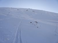 a person is skiing down the snow covered mountain slope, leaving trail markers and trails on the side of the hill