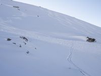 a person is skiing down the snow covered mountain slope, leaving trail markers and trails on the side of the hill