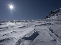 a man is skiing down a snowy slope at the bottom of the mountainside, with snow on the ground