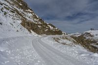 a person is cross country skiing down a snowy hill side slope to a mountain top