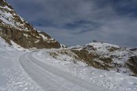 a person is cross country skiing down a snowy hill side slope to a mountain top