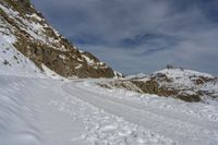 a person is cross country skiing down a snowy hill side slope to a mountain top