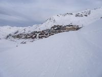 snow covered slope in the middle of a ski area as people ski on it near ski lift