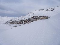 snow covered slope in the middle of a ski area as people ski on it near ski lift