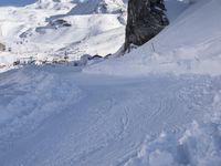 a man riding skis down a snow covered slope next to tall buildings on a mountain